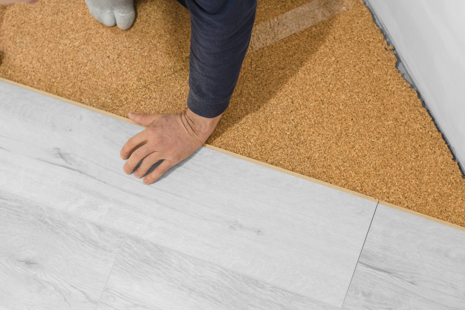 Unrecognizable man laying laminate flooring. Repair in the apartment. Professional laying of a floor covering - a laminate. Laminate installation process